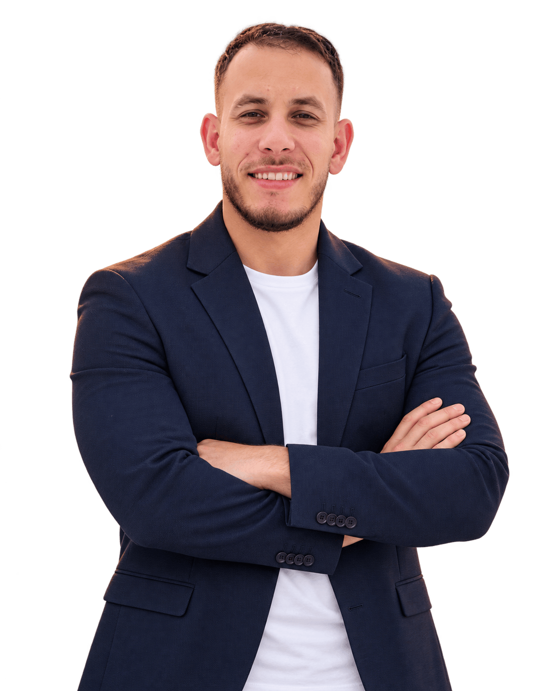 يونس حروكة مبتسم ويرتدي سترة كحلية وقميصاً أبيض، وذراعاه متقاطعتان.